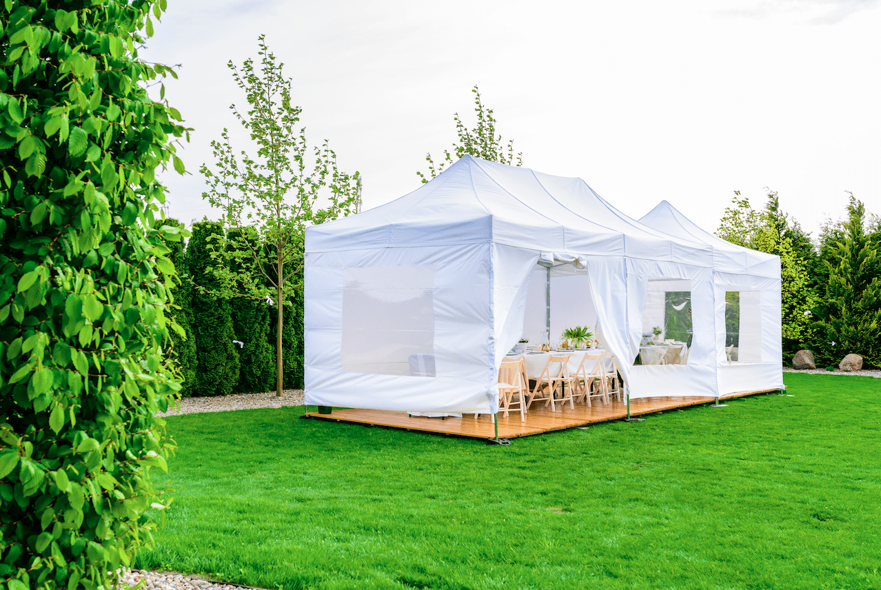White outdoor event tent setup on a green lawn for weddings and summer gatherings